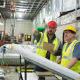 Two men with hardhats and safety glasses in warehouse