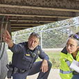 Police officer with truck driver inspecting under semi