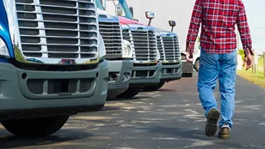 Man walking past front of parked semi trucks