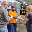 Coworkers meet by barrels of chemicals.