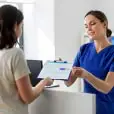 Nurse provides paperwork to woman.