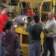 Group of coworkers having discussion by manufacturing equipment.