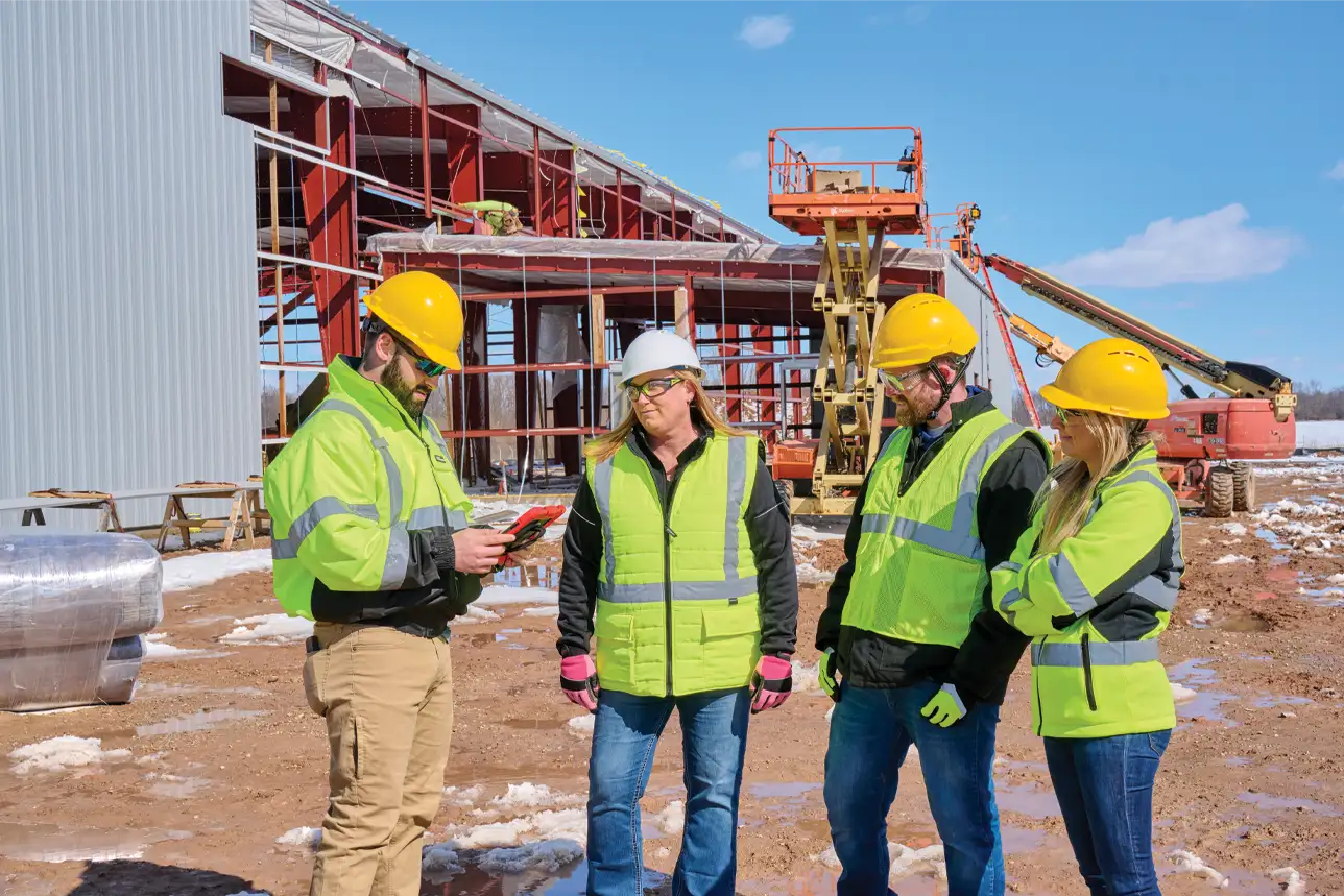 Several workers meeting on a construction site wearing proper PPE
